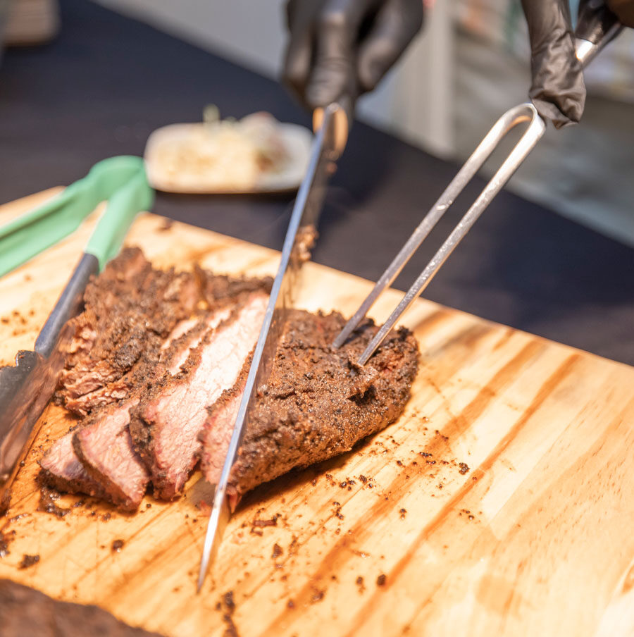 A chef carves a deliciously seasoned piece of meat, preparing a mouthwatering dish for residents at the senior living community.