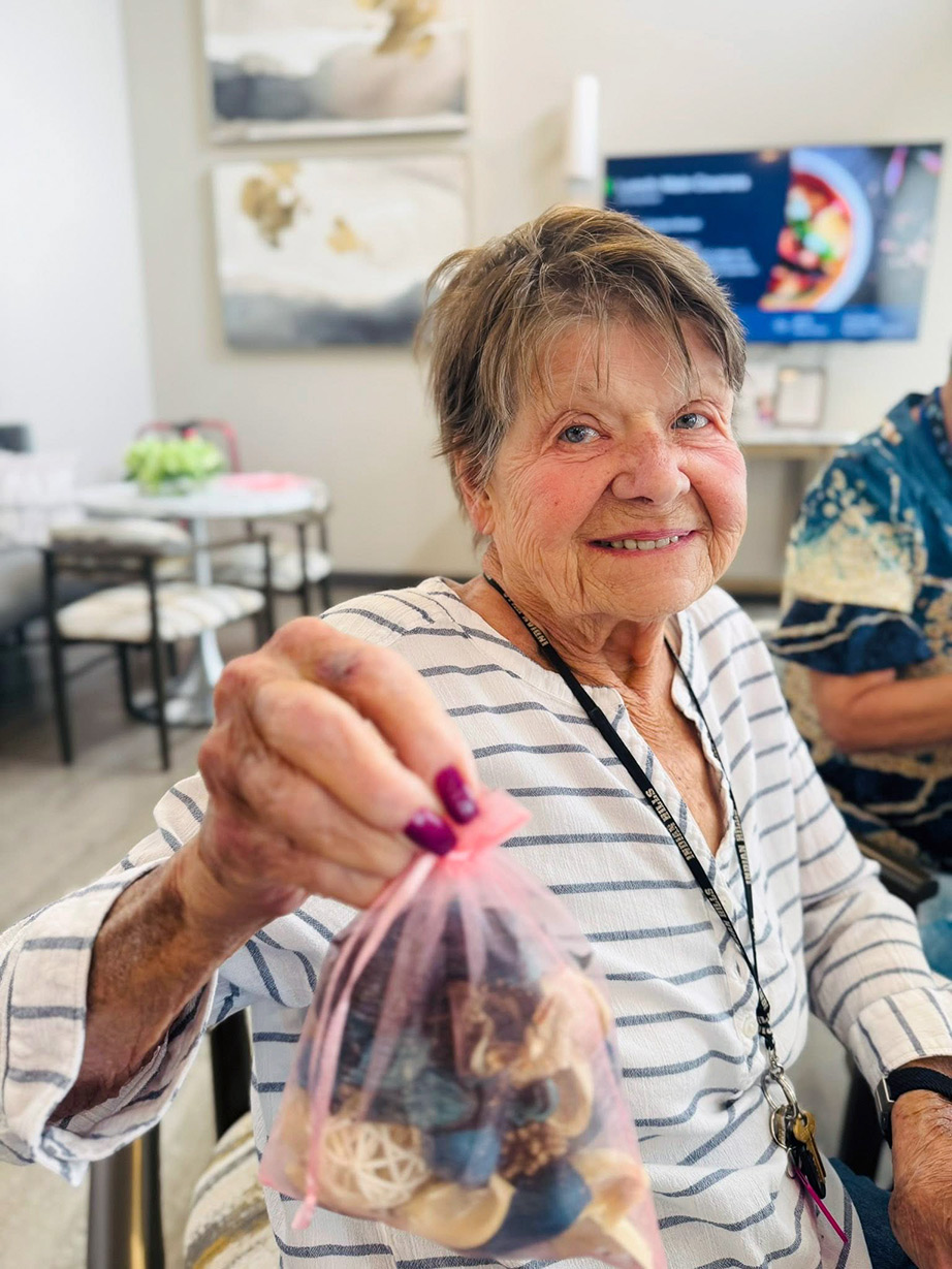 A resident holds up a mesh bag of potpourri made during a community event.