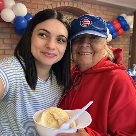 A team member and smiling senior resident enjoy a themed event with ice cream.