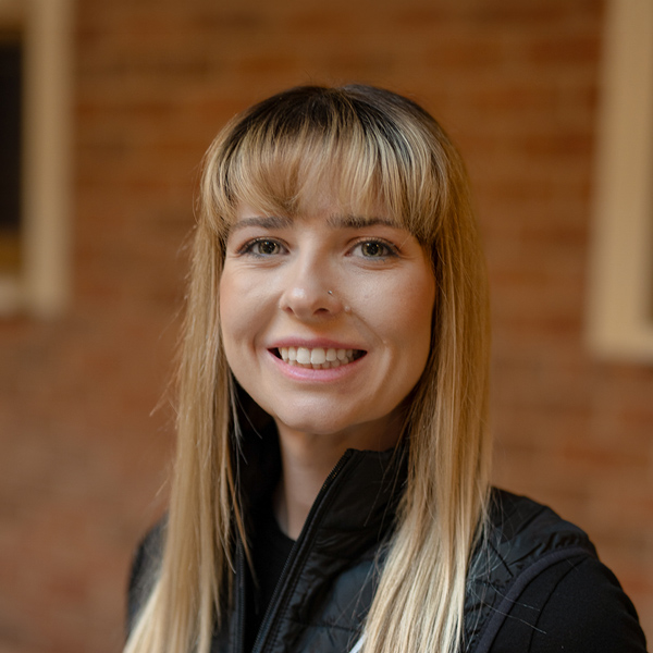 Kristen Hawkins-Hamer, Business Office Director at Walden Place Senior Living, smiling in a professional headshot, wearing a black vest, with a softly blurred brick background.